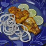 Serve fried fish ajwaini with lemon wedges and onion rings