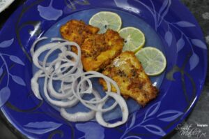 Serve fried fish ajwaini with lemon wedges and onion rings