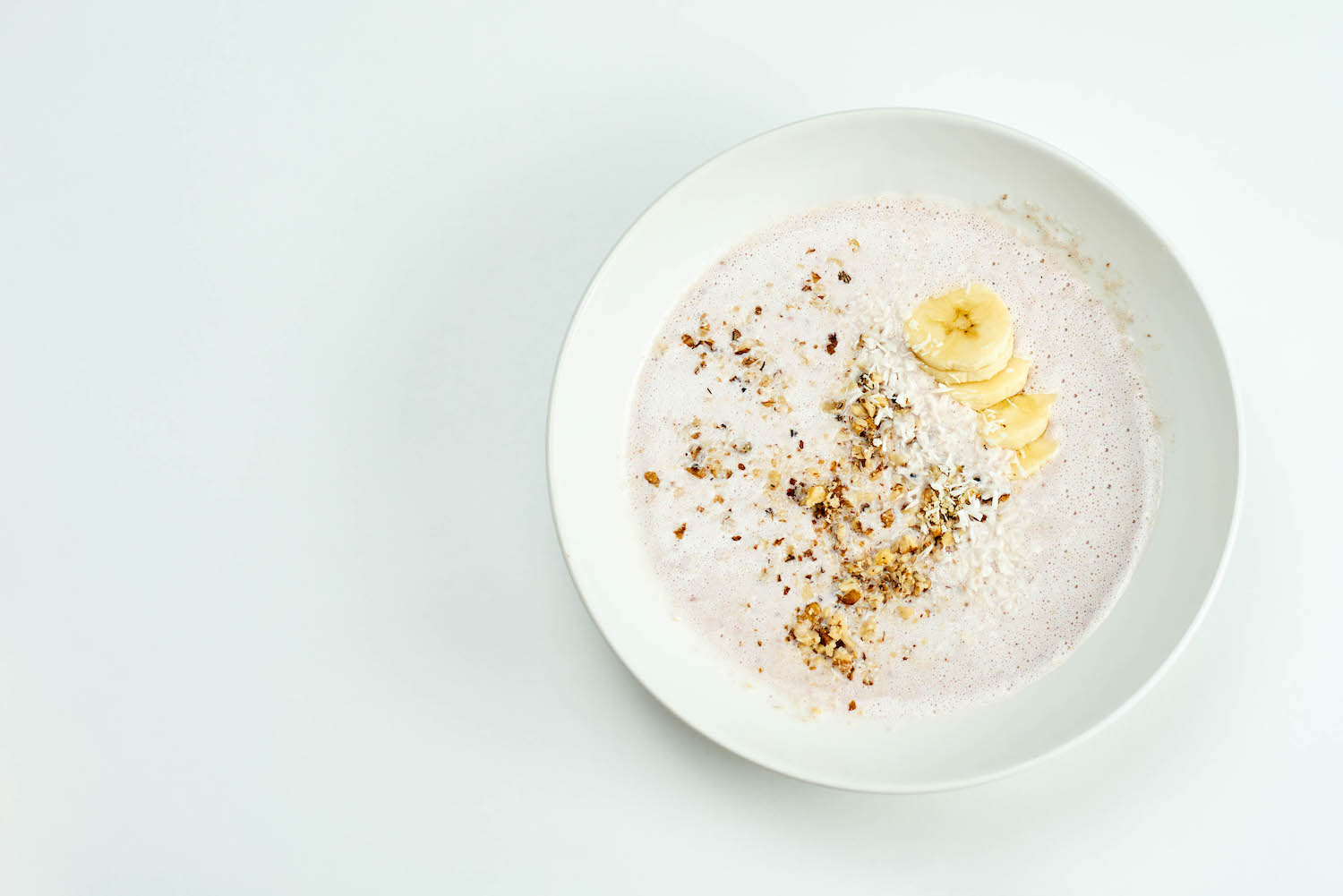 A bowl of refreshing banana and oats smoothie based smoothie with walnut shreds
