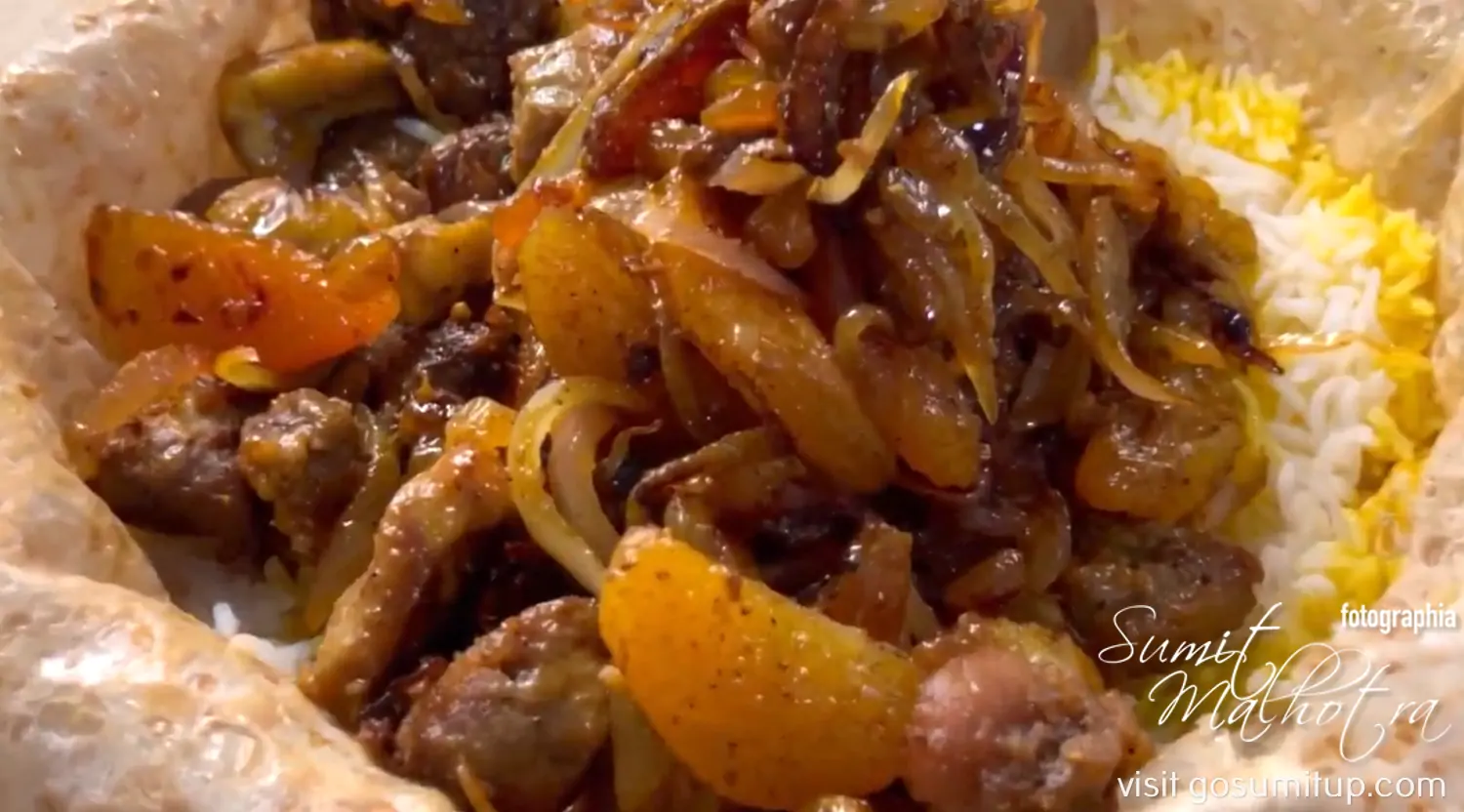 Meat being added to the first layer of rice for shah plov