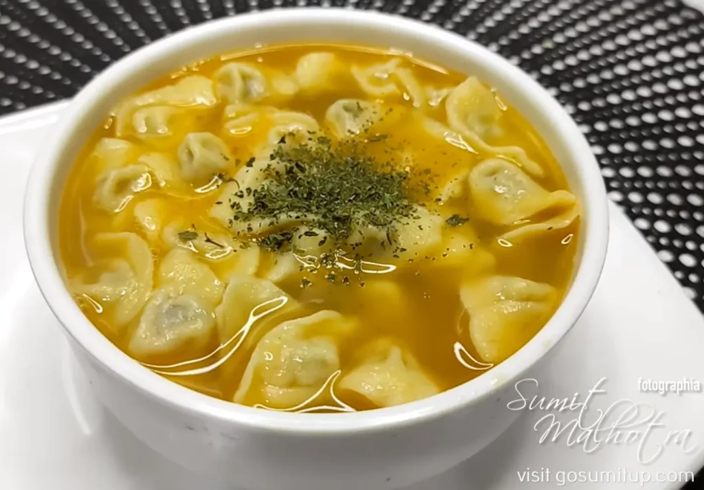 Home A traditional azerbaijani wooden spoon filled with dozens of microscopic, perfectly folded dushbara dumplings in a golden clear broth.